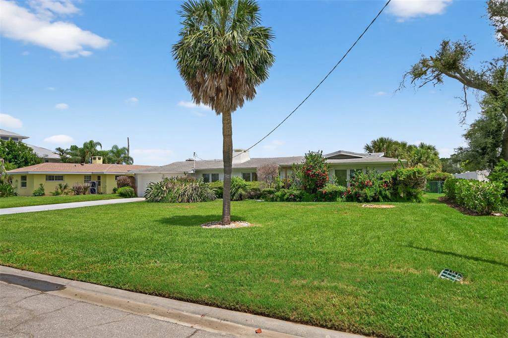 A single-story house with a palm tree in the front yard under a blue sky — 377 S SHORE DRIVE, SARASOTA, FL