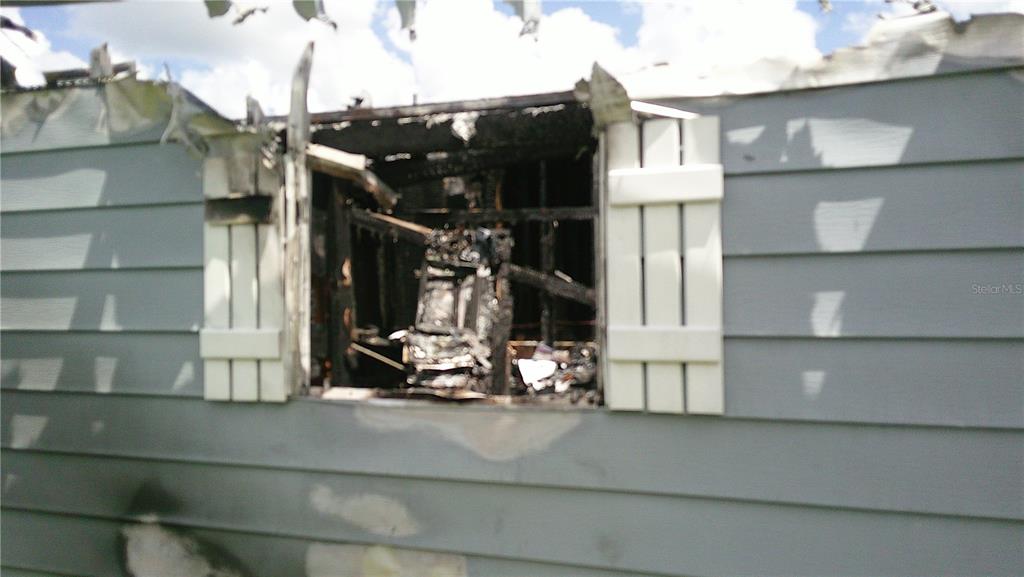 The exterior of a house shows a window opening with severe fire and smoke damage — 6710 36TH AVENUE E UNIT 326, PALMETTO, FL