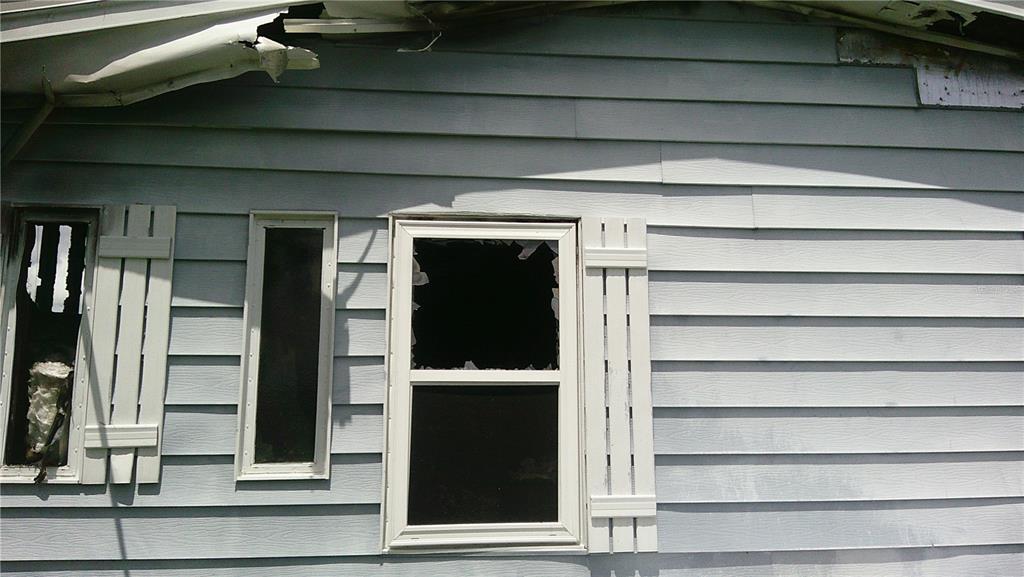 Exterior view of a house with light blue siding, broken windows, and damaged roof eaves — 6710 36TH AVENUE E UNIT 326, PALMETTO, FL