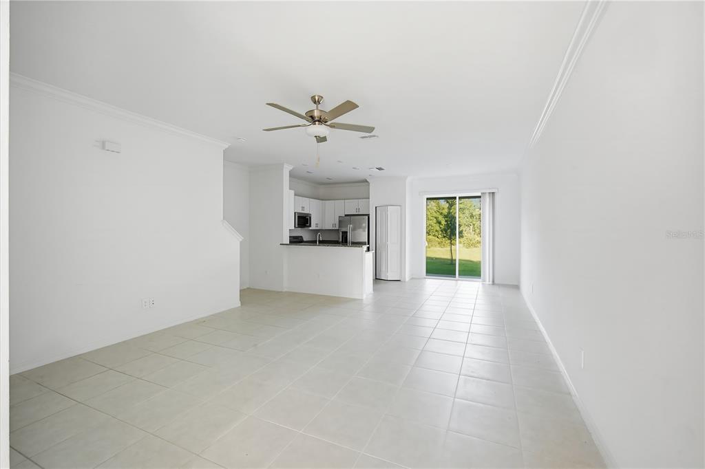 An open-concept living and dining area features white walls, tile flooring, and a kitchen — 10956 WISHING CLOUD ROAD, LAND O LAKES, FL