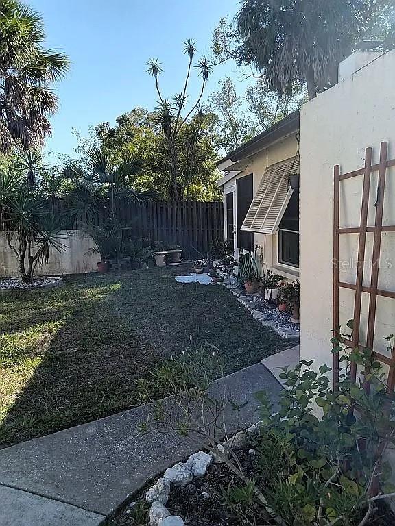 A backyard features a concrete walkway, a small lawn, potted plants, and a wooden trellis — 5366 ROYAL PALM AVENUE UNIT 5366, SARASOTA, FL
