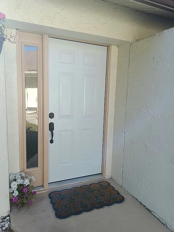 A white front door with a side window and a patterned mat on the porch — 5366 ROYAL PALM AVENUE UNIT 5366, SARASOTA, FL