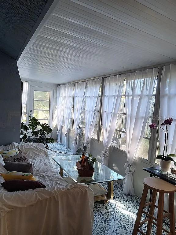A sunroom features a white sofa, a glass coffee table, and floor-to-ceiling windows with curtains — 5366 ROYAL PALM AVENUE UNIT 5366, SARASOTA, FL