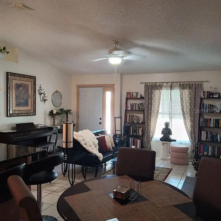 A living and dining area features a ceiling fan, bookshelves, a piano, and tile flooring — 5366 ROYAL PALM AVENUE UNIT 5366, SARASOTA, FL