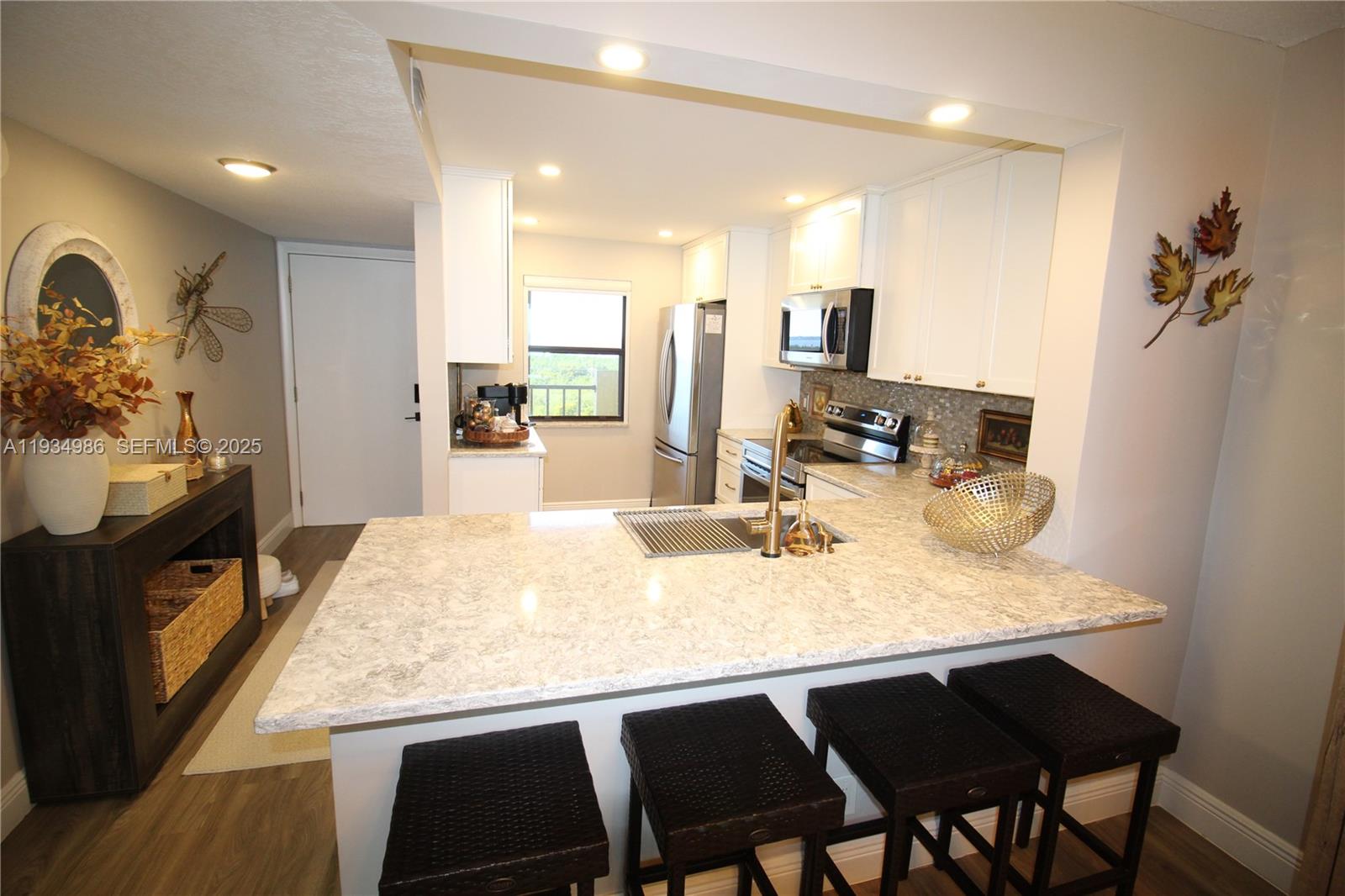 A kitchen features white cabinets, a stone countertop, a breakfast bar, and stainless appliances — 7370 S Ocean Dr # 715, Jensen Beach FL 34957, JENSEN BEACH, FL