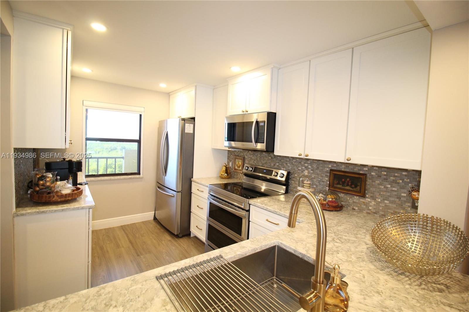 A kitchen features white cabinets, stainless steel appliances, granite countertops, and a mosaic tile backsplash — 7370 S Ocean Dr # 715, Jensen Beach FL 34957, JENSEN BEACH, FL