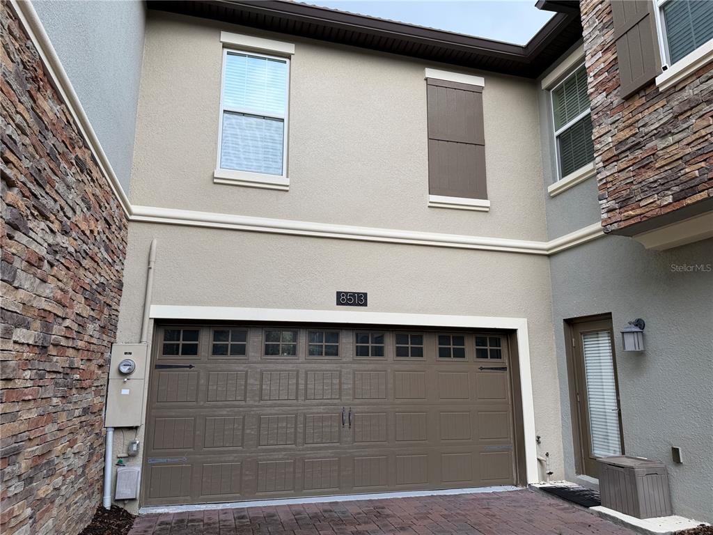 The exterior of a two-story home features a brown garage door and stone accents — 8513 GOLF WAY, DAVENPORT, FL