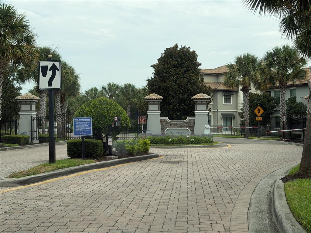 A gated entrance with a stone monument sign reading The Vistas and paved driveway — 8513 GOLF WAY, DAVENPORT, FL