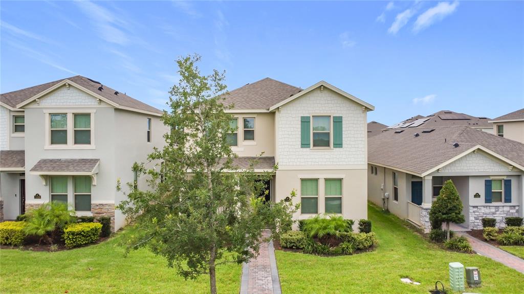 A two-story suburban house with a beige exterior, green shutters, and a paved walkway — 11045 BOSTWICK ALLEY, WINTER GARDEN, FL
