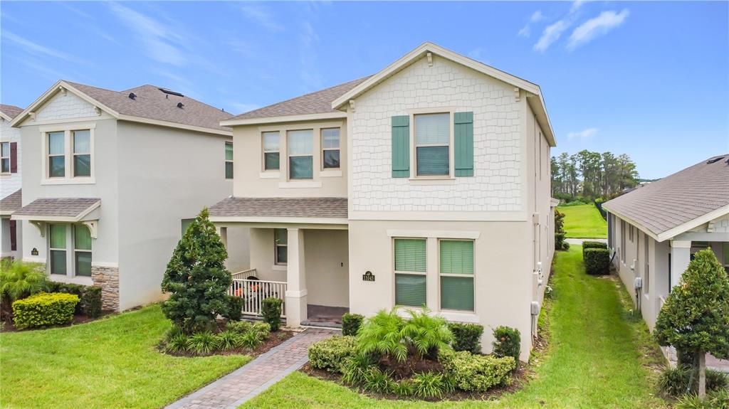 A two-story suburban house with a covered front porch and a brick walkway — 11045 BOSTWICK ALLEY, WINTER GARDEN, FL