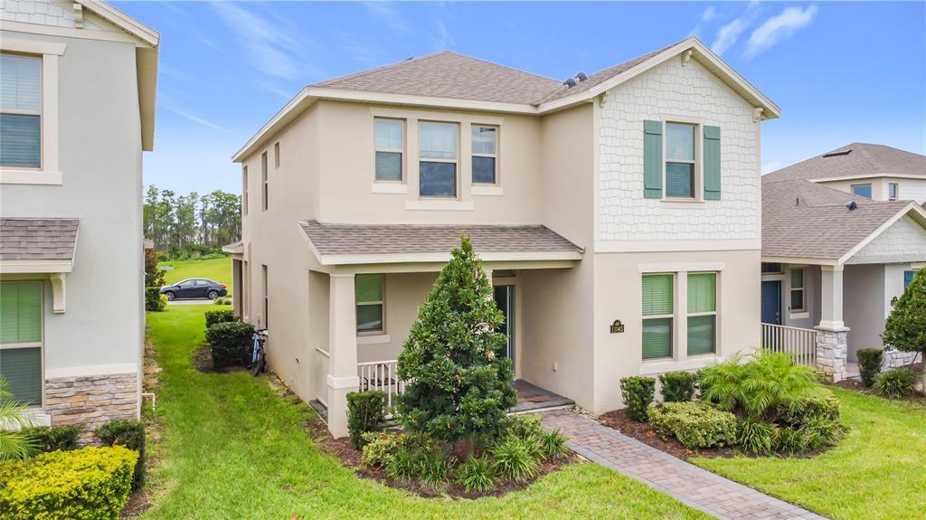A two-story suburban house with a tan stucco exterior, shingled roof, and a front porch — 11045 BOSTWICK ALLEY, WINTER GARDEN, FL