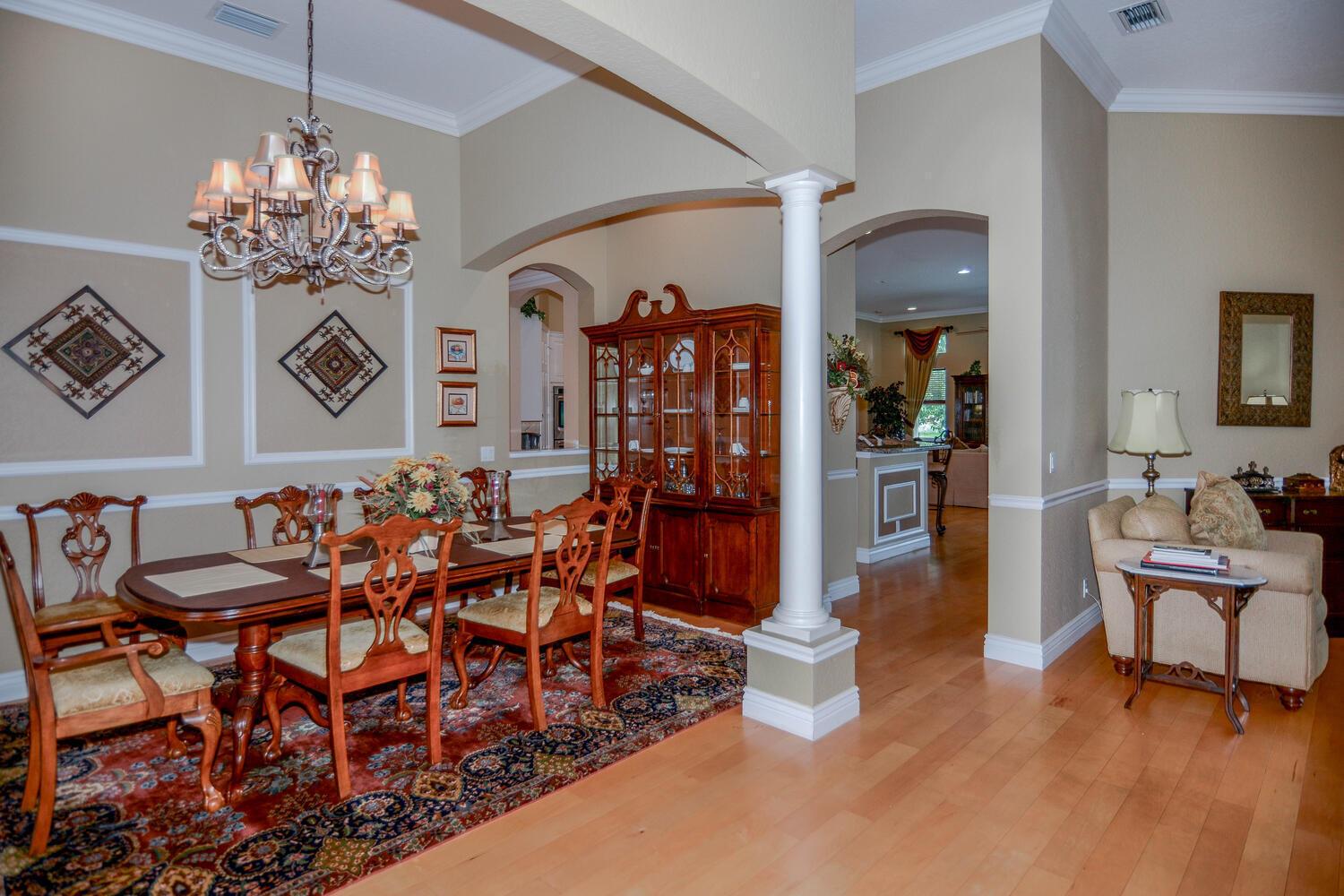 A formal dining room features a wooden table, chandelier, china cabinet, and hardwood flooring — 4676 Manderly Drive, Wellington FL 33449, WELLINGTON, FL