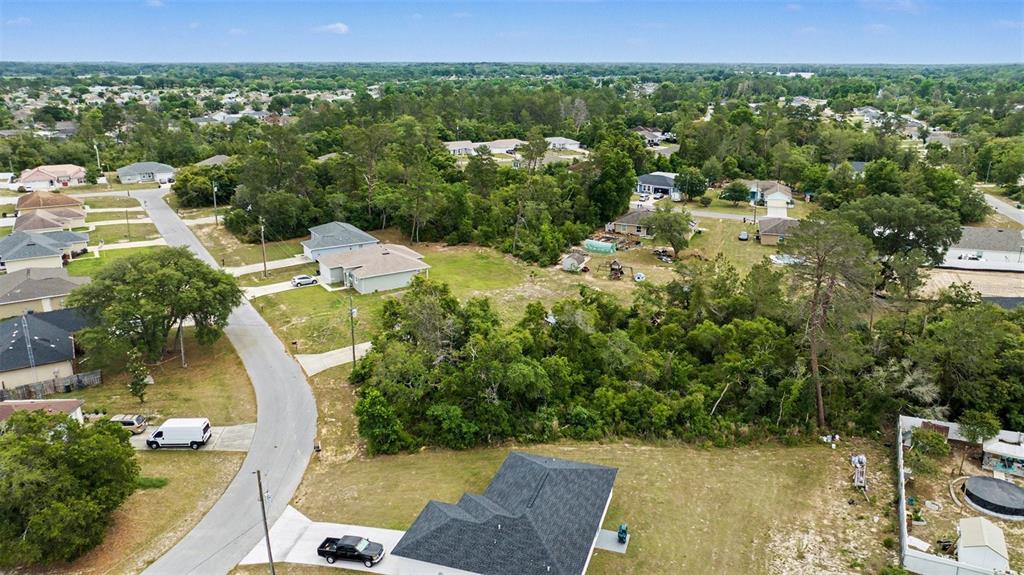 An aerial view shows a suburban neighborhood with houses, wooded areas, and a paved road — 00000 SW 23RD AVENUE ROAD, OCALA, FL