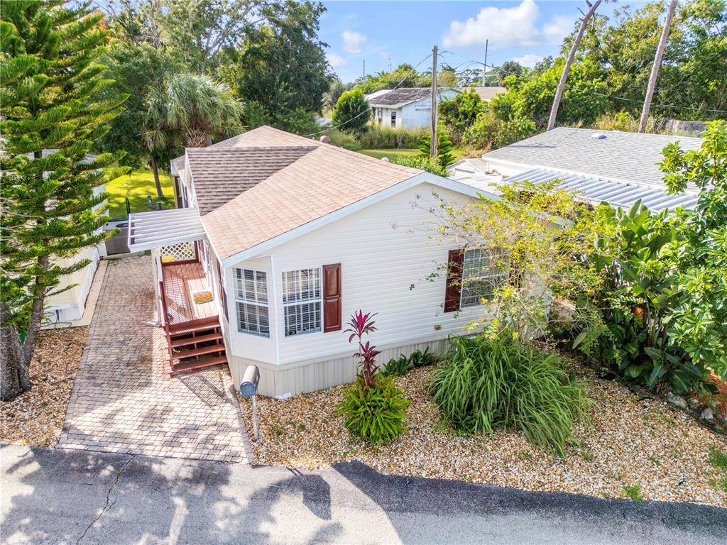 An elevated exterior view of a single-story home with light siding, brown shutters, and landscaping — 2201 S RIDGEWOOD AVENUE UNIT 28, EDGEWATER, FL