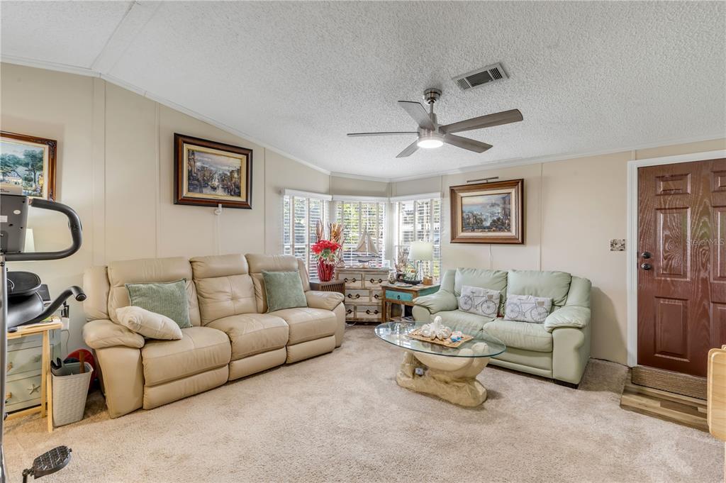 A living room features two leather sofas, a glass coffee table, and a ceiling fan — 2201 S RIDGEWOOD AVENUE UNIT 28, EDGEWATER, FL