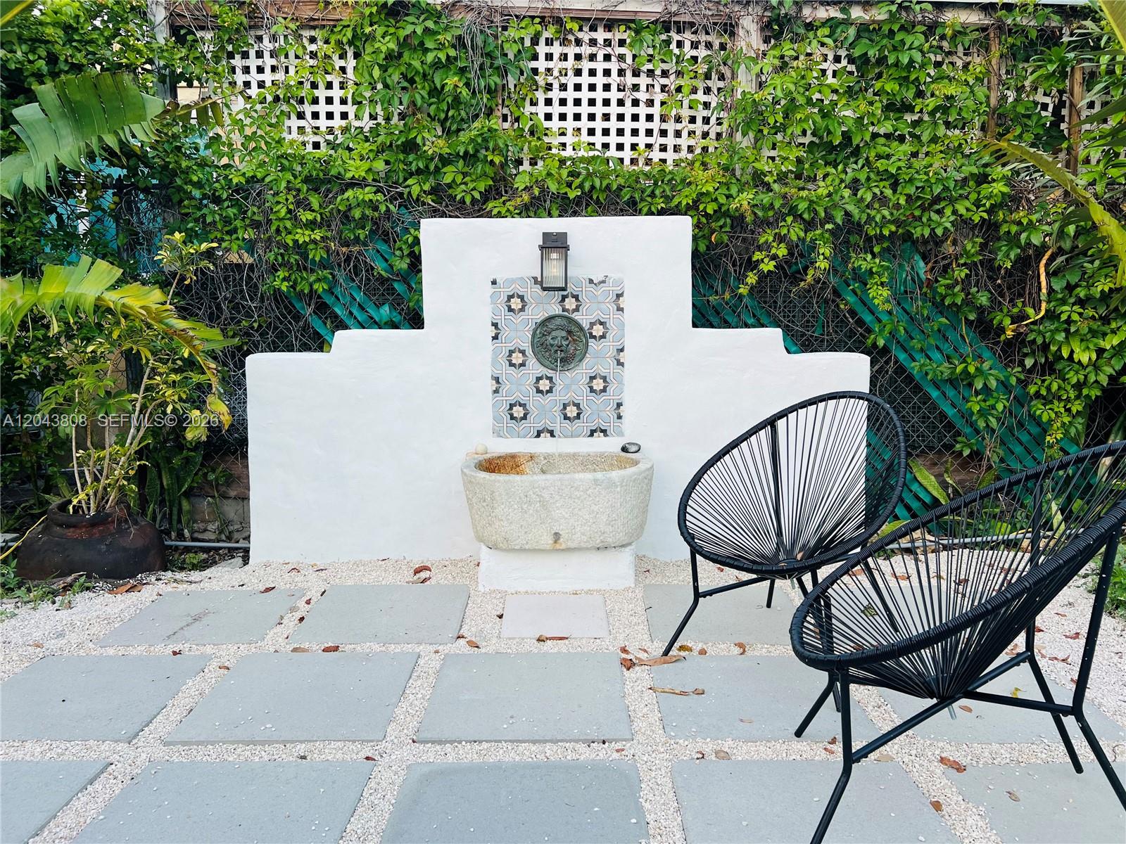 A stone fountain with a lion head spout sits on a patio with two chairs — 2134 SW 11th St, Miami FL 33135, MIAMI, FL