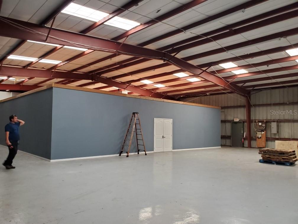A large warehouse interior features a blue partition wall with double doors and a ladder — 9737 NEW YORK AVENUE, HUDSON, FL