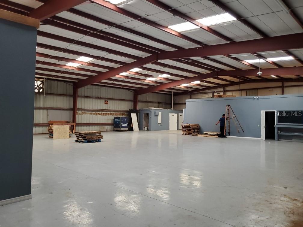 A large, open warehouse space features a gray epoxy floor and exposed metal ceiling beams — 9737 NEW YORK AVENUE, HUDSON, FL