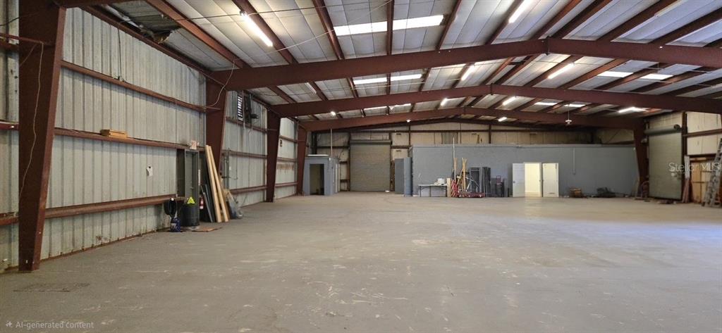 An expansive, open-plan warehouse interior features exposed steel beams, concrete flooring, and metal walls — 9737 NEW YORK AVENUE, HUDSON, FL