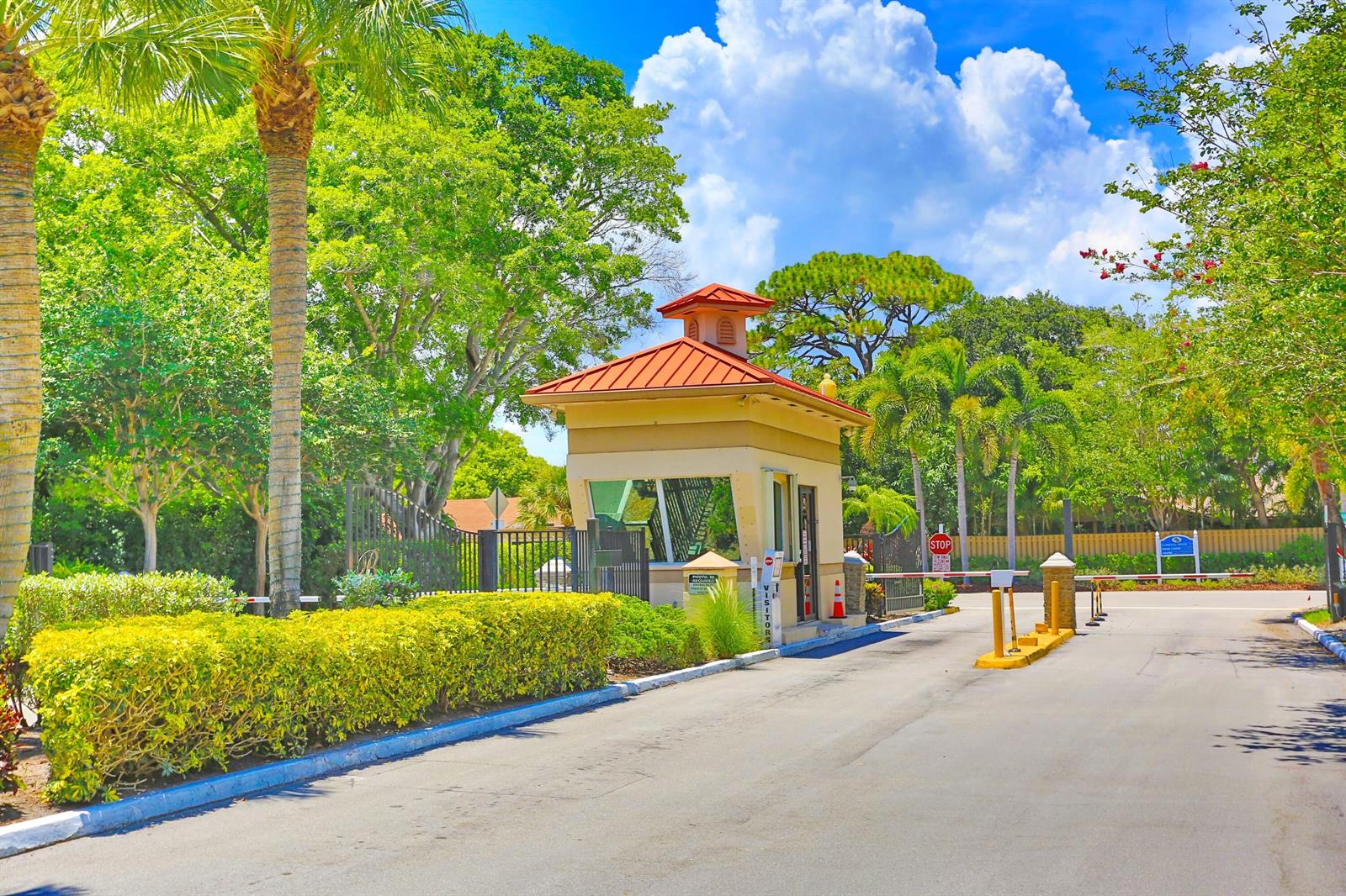 A gated community entrance features a small guardhouse with a red metal roof and landscaping — 714 NW 27th Avenue # C, Delray Beach FL 33445, DELRAY BEACH, FL