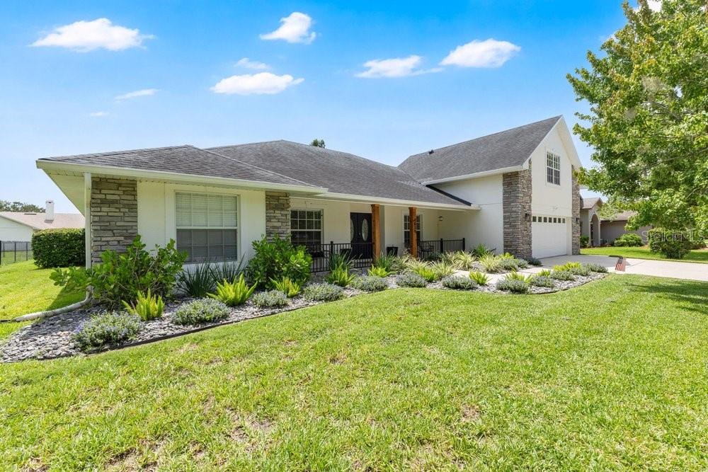 A single-story house with a white exterior, stone accents, and a landscaped front yard — 4839 CALASANS AVENUE, ST CLOUD, FL