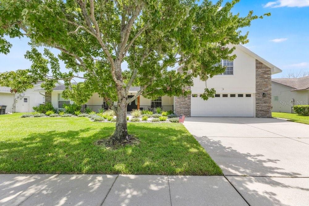 A two-story house with a white stucco facade, stone accents, and a large front tree — 4839 CALASANS AVENUE, ST CLOUD, FL