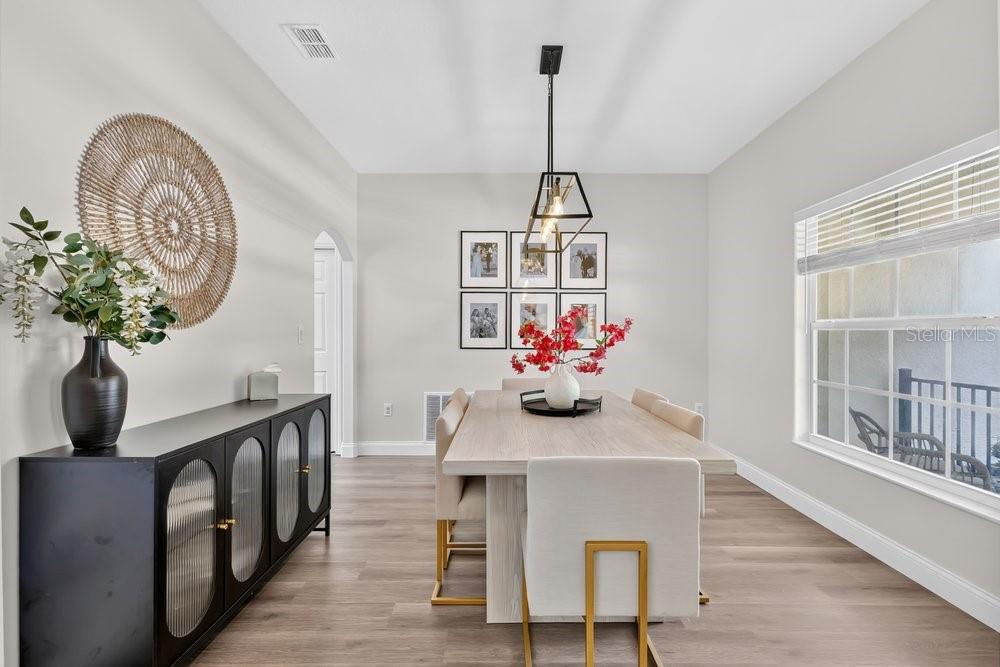 A dining room features a light wood table, upholstered chairs, a black sideboard, and pendant lighting — 4839 CALASANS AVENUE, ST CLOUD, FL
