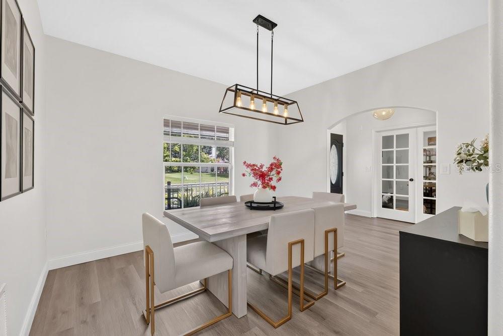 A dining room features a light wood table, upholstered chairs with gold legs, and a chandelier — 4839 CALASANS AVENUE, ST CLOUD, FL