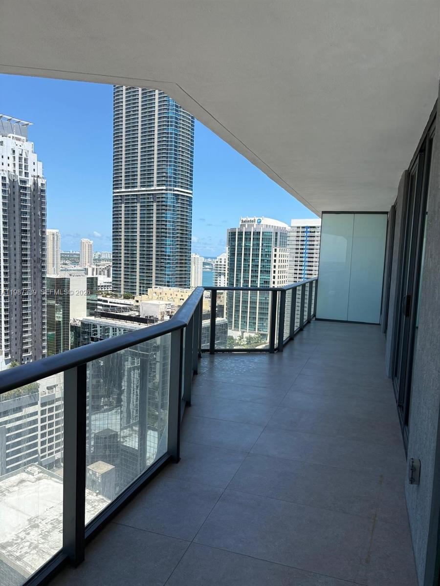 A high-rise balcony features glass railings and tile flooring overlooking a dense urban cityscape — 1300 S Miami Ave # 2911, Miami FL 33130, MIAMI, FL
