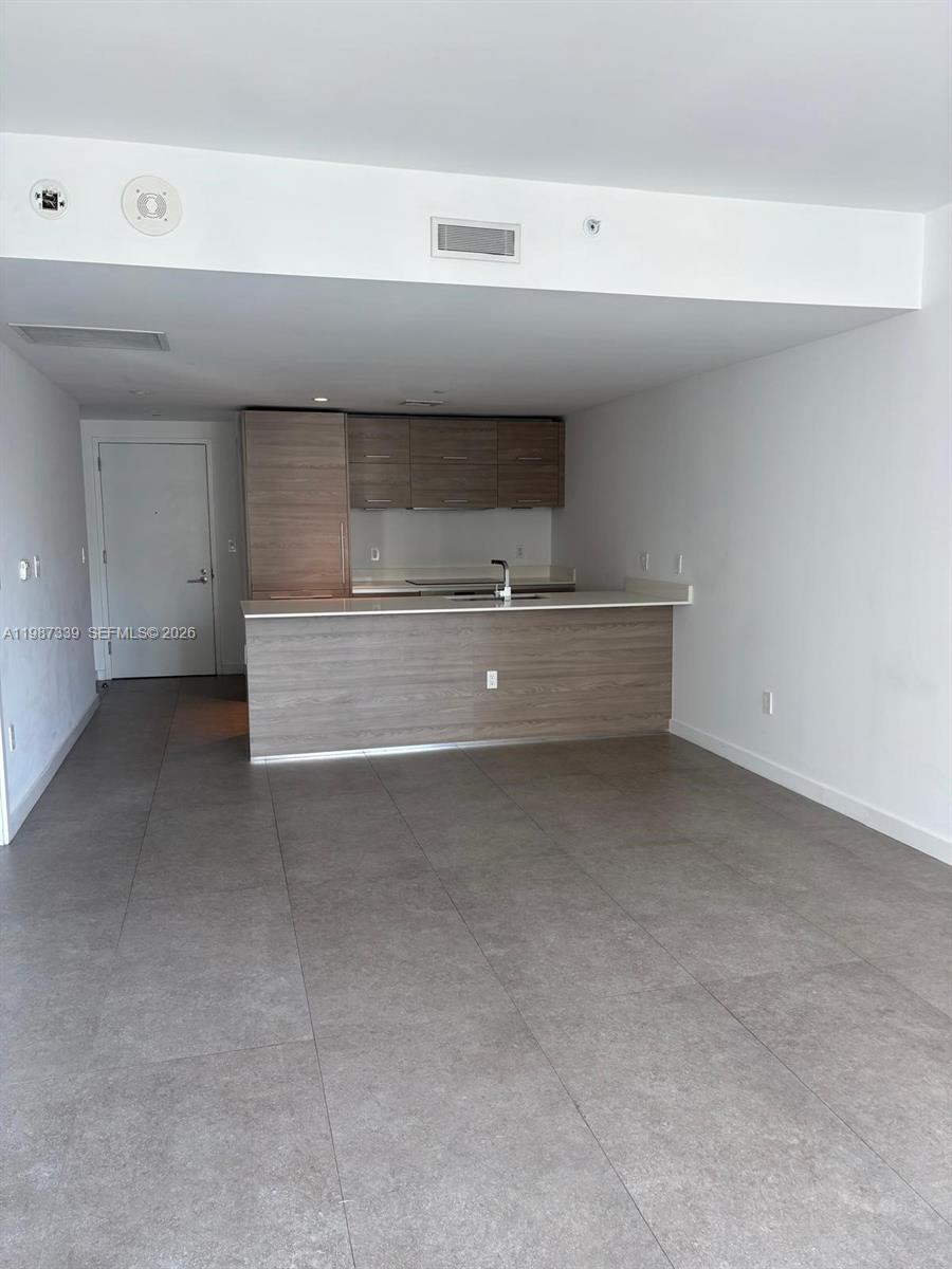 This open-concept kitchen features wood-toned cabinetry, a breakfast bar, and gray tile flooring — 1300 S Miami Ave # 2911, Miami FL 33130, MIAMI, FL
