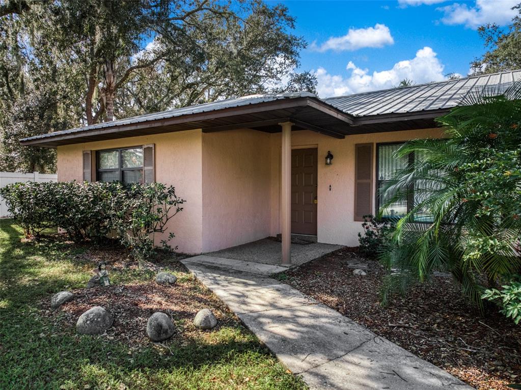 A single-story house with a pink stucco exterior, metal roof, and a covered front entrance — 1771 N TORRINGTON ROAD, AVON PARK, FL