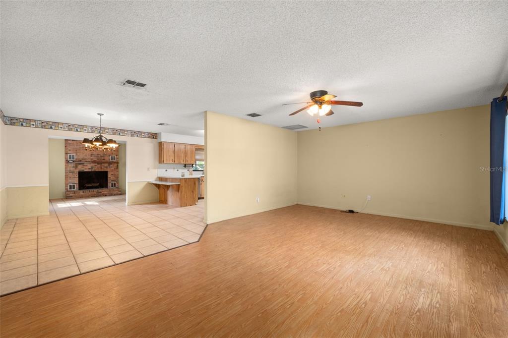 A living room with wood-look flooring transitions into a tiled kitchen area with a fireplace — 1771 N TORRINGTON ROAD, AVON PARK, FL