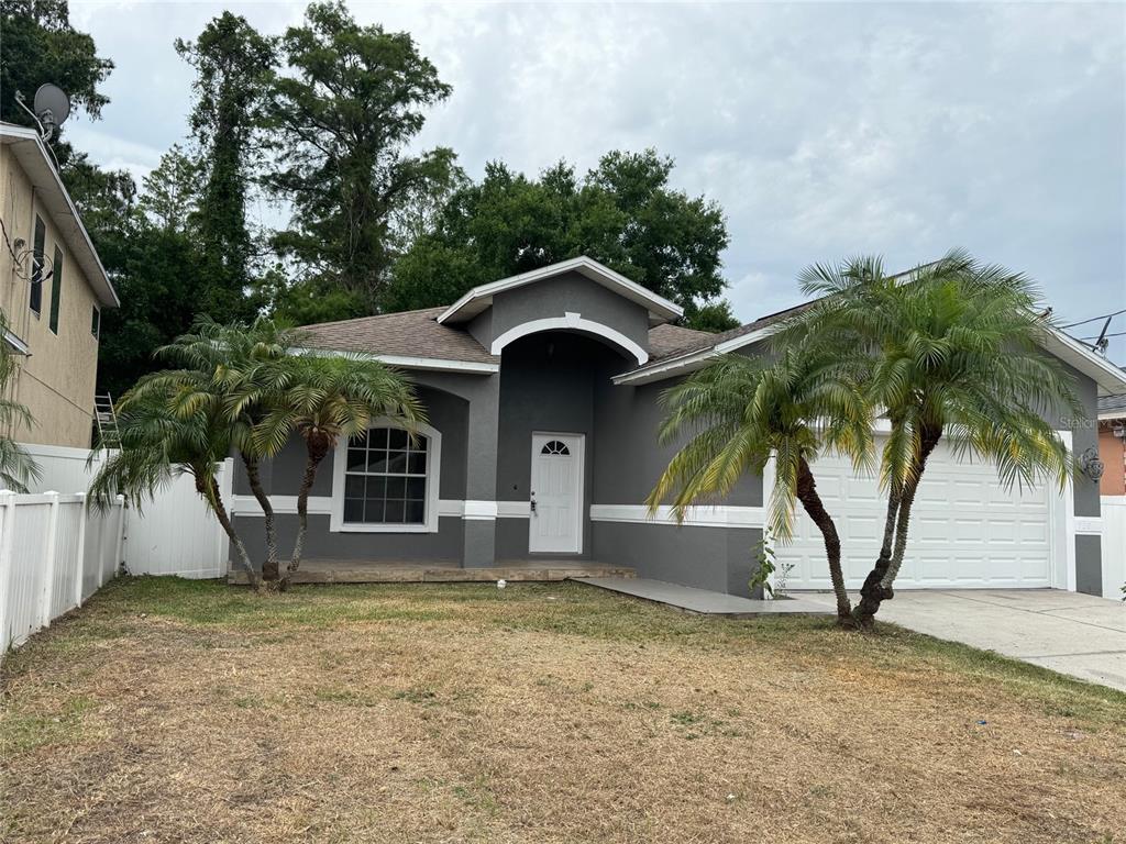 A gray single-story house with a white garage door, front porch, and two palm trees — 7202 N GLEN AVENUE, TAMPA, FL