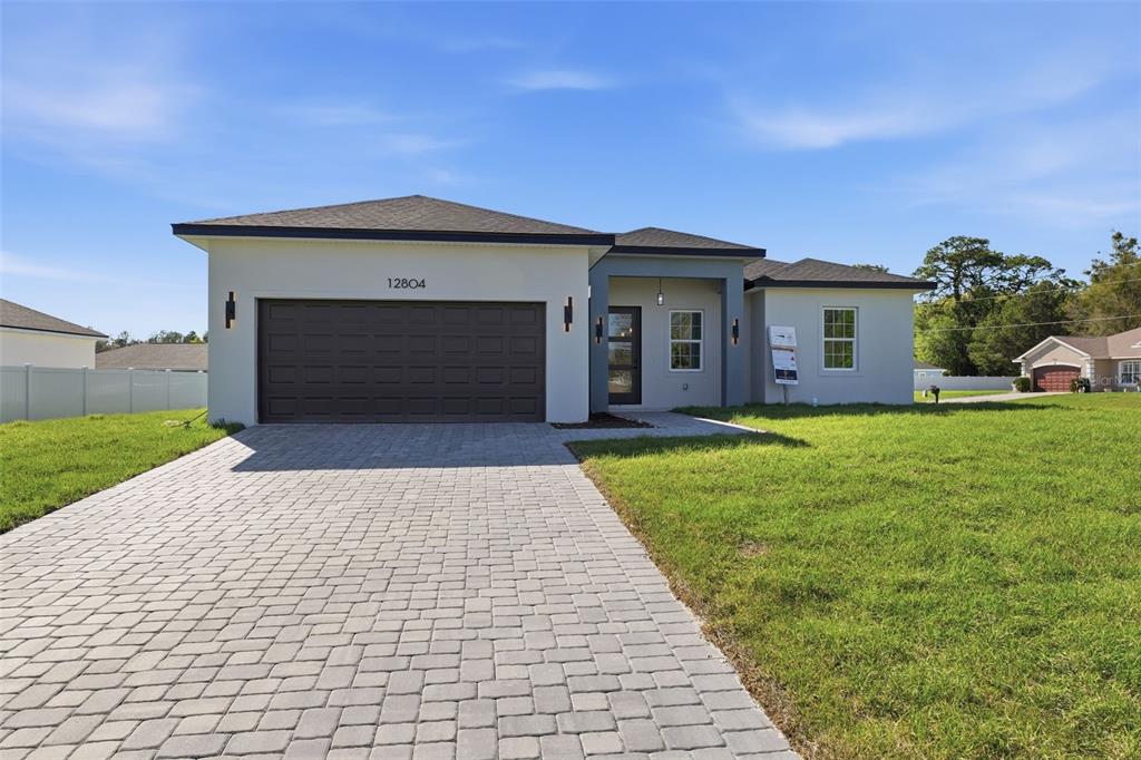 A modern single-story house features a paved driveway, a two-car garage, and a covered entryway — 12804 SW 74TH TERRACE, OCALA, FL