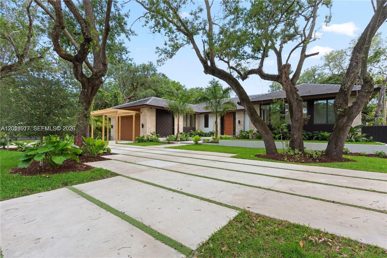 A modern single-story house with a concrete driveway and large oak trees in front — 7840 SW 98th St, Miami FL 33156, MIAMI, FL