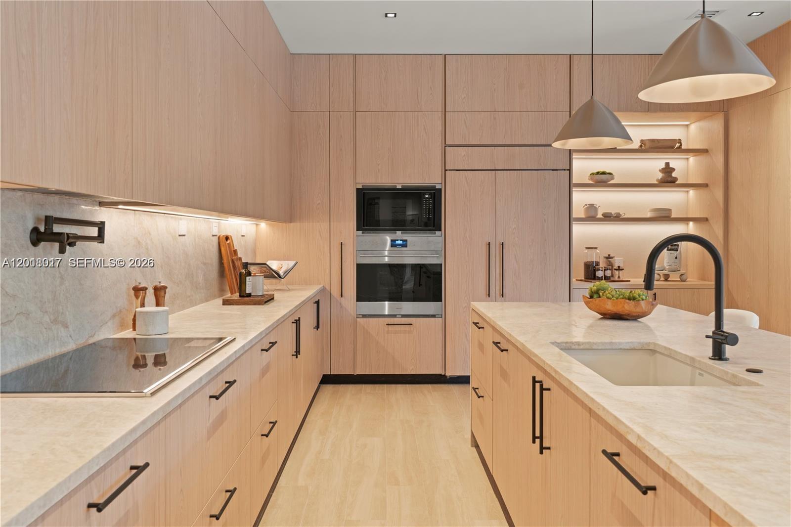 A modern kitchen features light wood cabinetry, marble countertops, and a central island with sink — 7840 SW 98th St, Miami FL 33156, MIAMI, FL