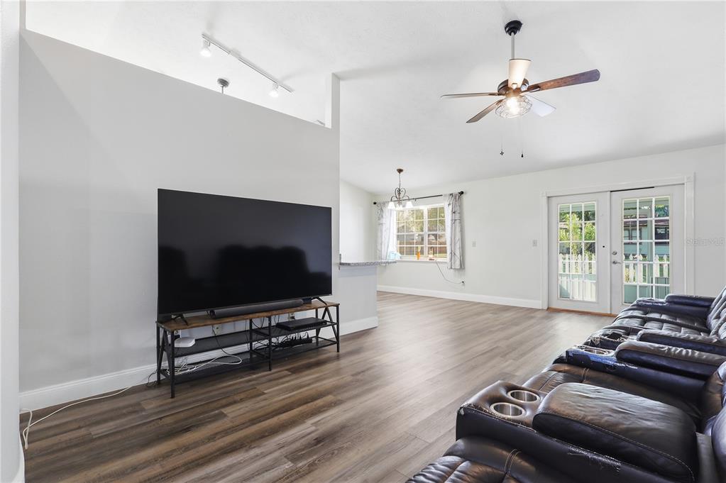 A living room features wood-look flooring, a large television on a metal stand, and a ceiling fan — 1405 E FRANCES AVENUE, PLANT CITY, FL