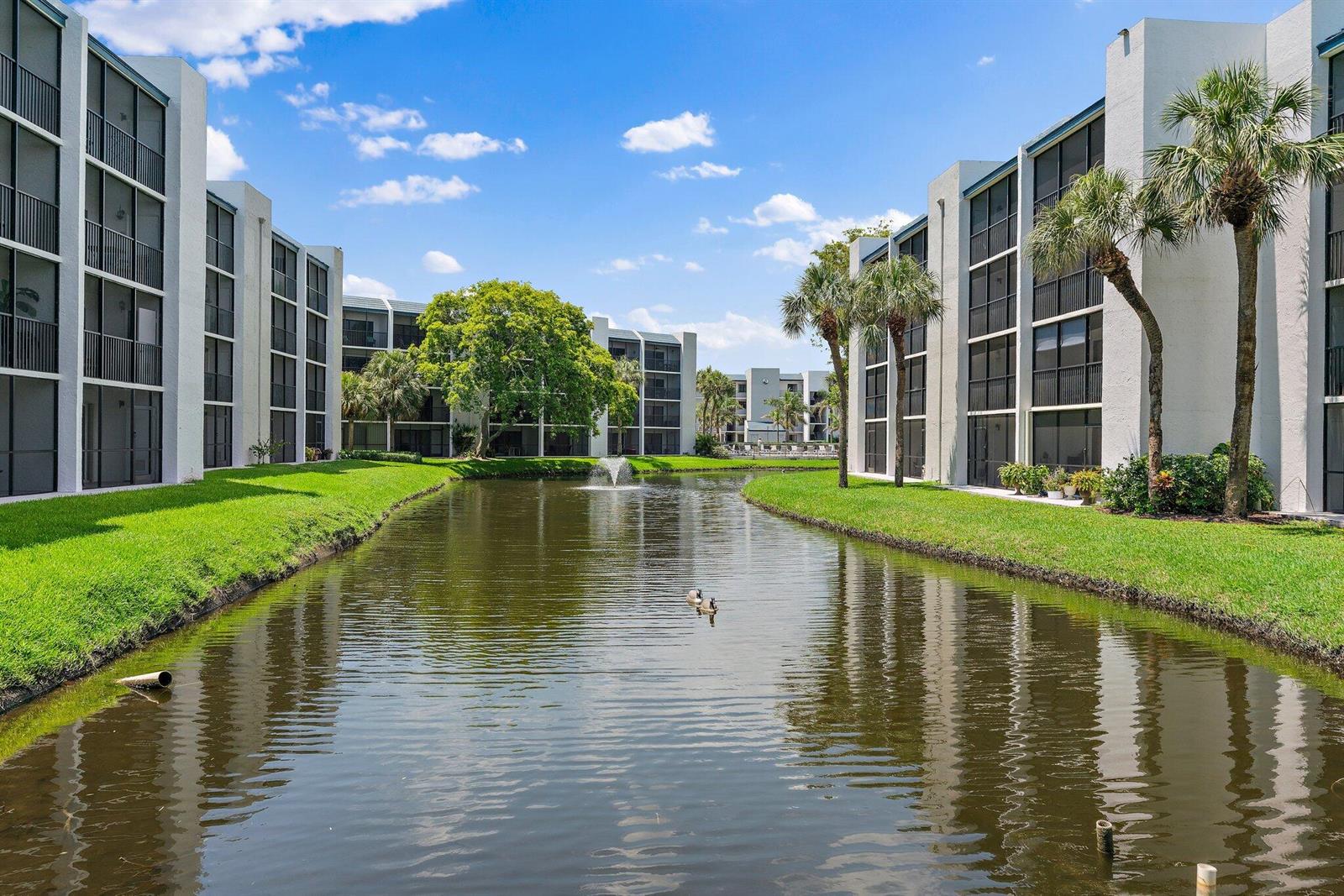 A pond with a fountain sits between two multi-story apartment buildings with screened balconies — 1605 S Us Highway 1 # D301, Jupiter FL 33477, JUPITER, FL