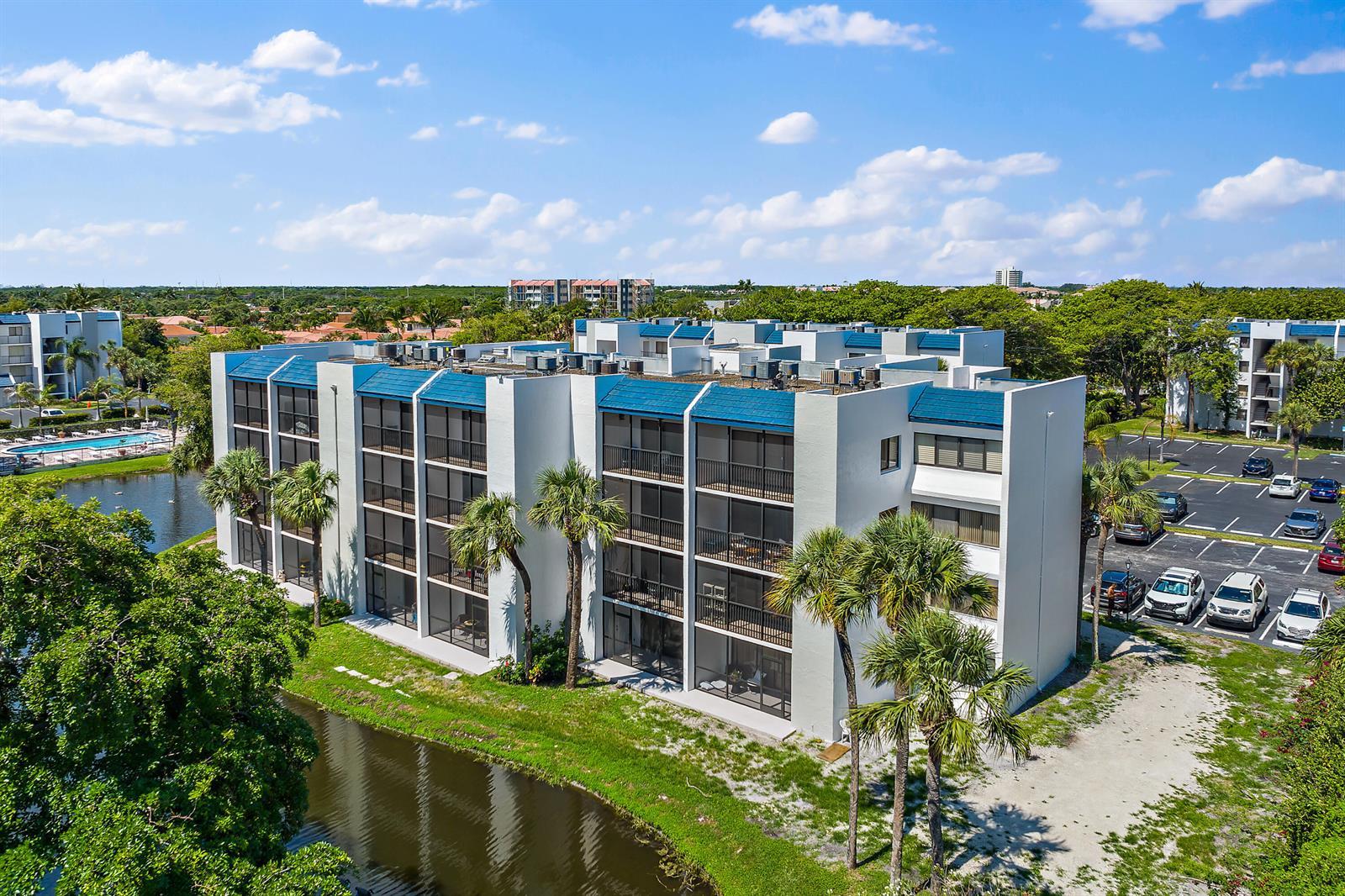 An aerial view of a multi-story apartment building with blue roofs, screened balconies, and parking — 1605 S Us Highway 1 # D301, Jupiter FL 33477, JUPITER, FL