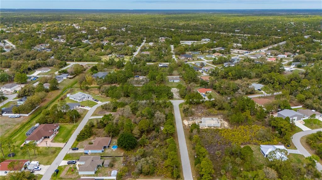 An aerial view shows a residential neighborhood with houses scattered among trees and vacant lots — PAIGO LANE, NORTH PORT, FL