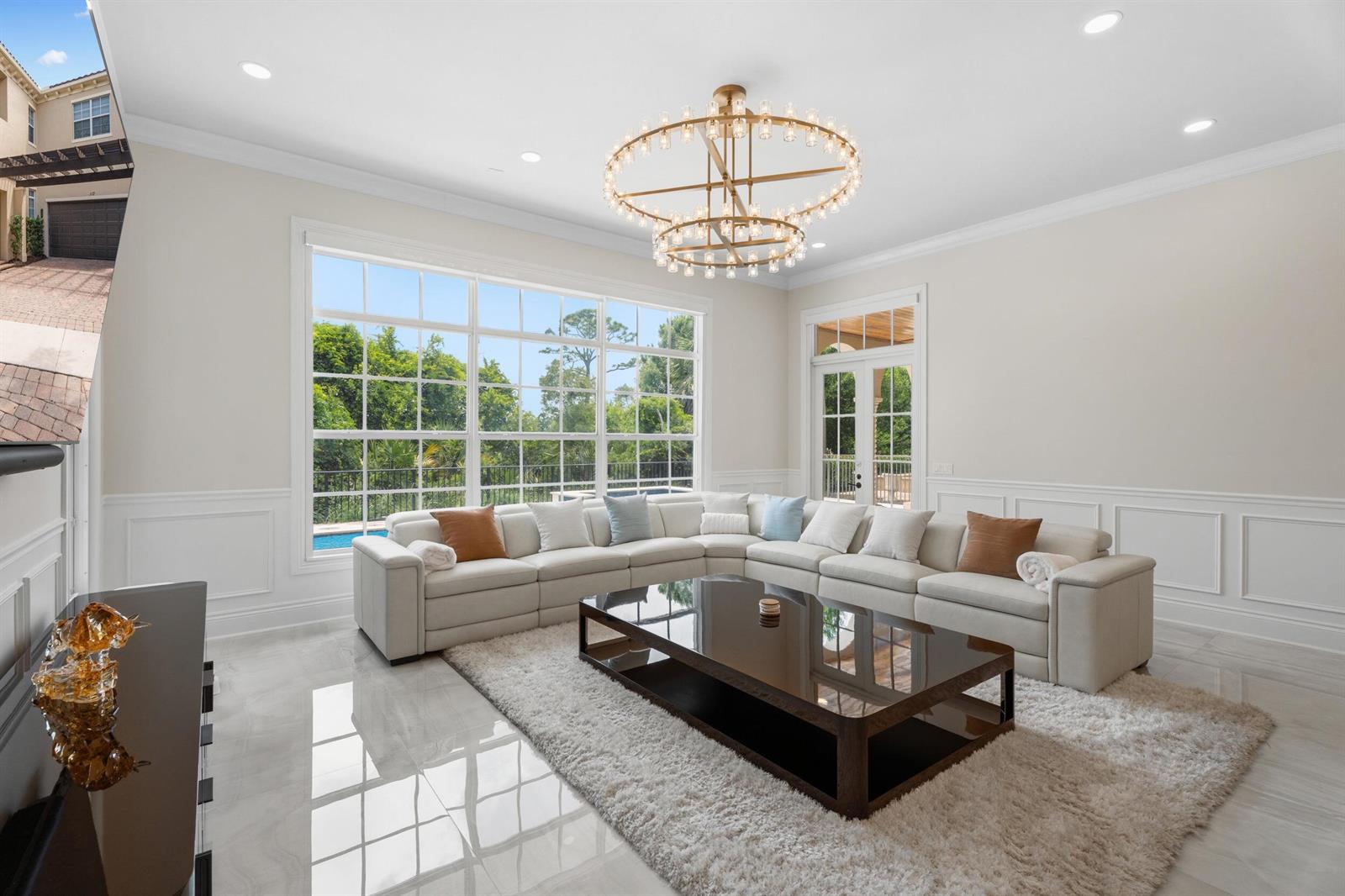 A bright living room features a large sectional sofa, a glass coffee table, and a chandelier — 112 Tulip Tree Court, Jupiter FL 33458, JUPITER, FL