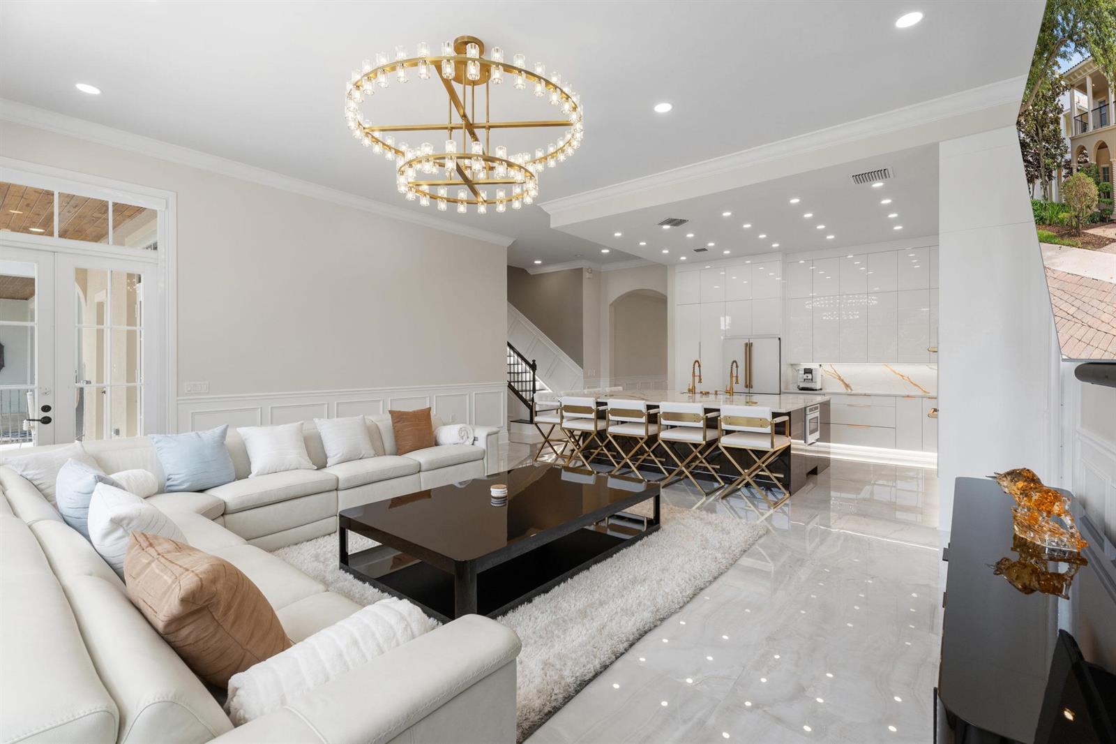A modern open-concept living room and kitchen with white cabinetry, gold accents, and marble flooring — 112 Tulip Tree Court, Jupiter FL 33458, JUPITER, FL