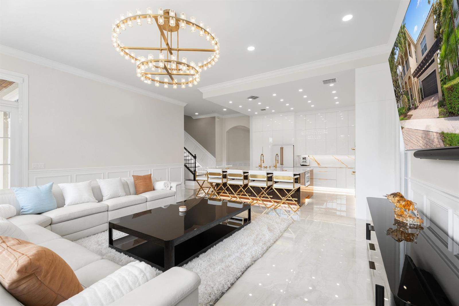 A modern open-concept living room and kitchen featuring white cabinetry, gold accents, and tile flooring — 112 Tulip Tree Court, Jupiter FL 33458, JUPITER, FL