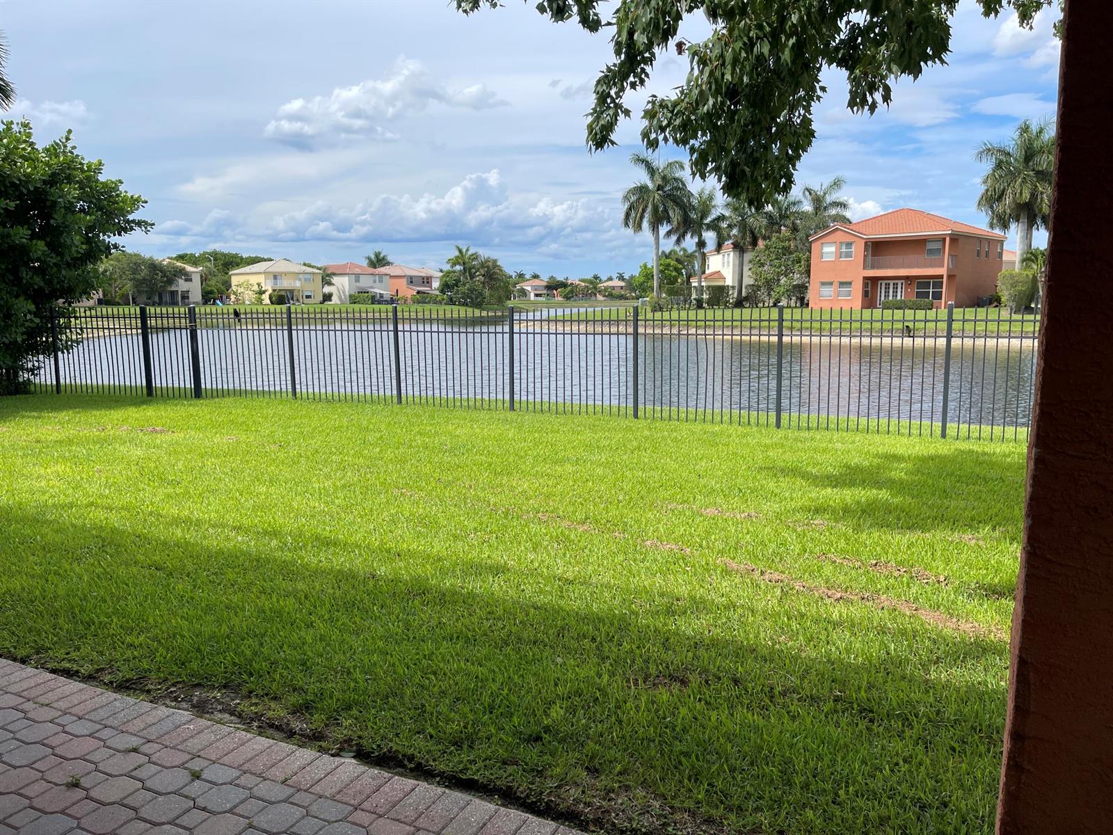 A backyard lawn with a metal fence overlooking a lake and residential houses — 9828 Stover Way, Wellington FL 33414, WELLINGTON, FL