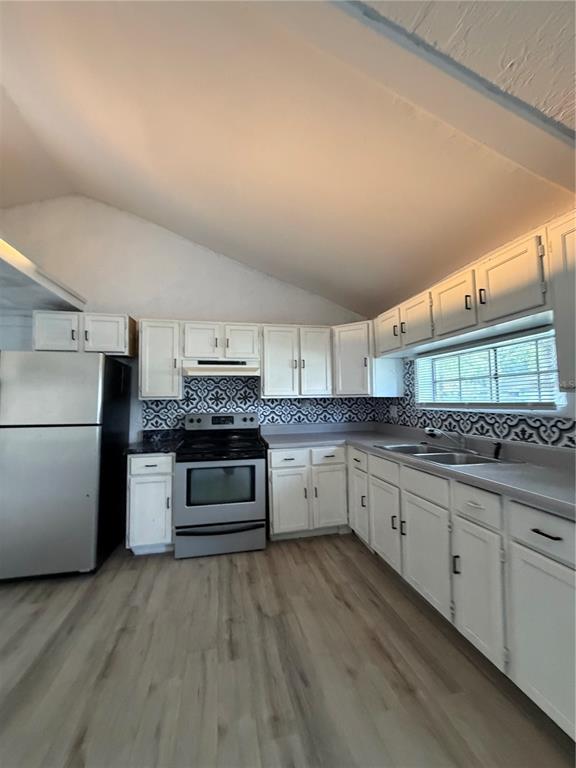 A kitchen features white cabinets, patterned backsplash tile, stainless steel appliances, and light wood flooring — 1505 N ORANGE STREET, PLANT CITY, FL
