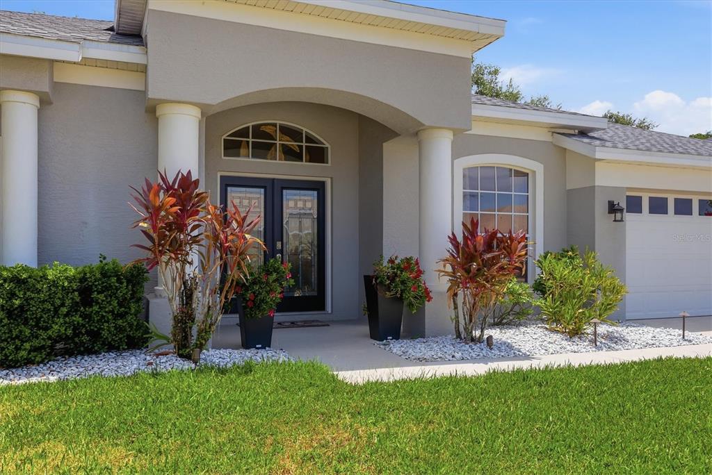 The exterior of a house features a covered entryway with columns and a double door — 4617 EGMONT DRIVE, BRADENTON, FL