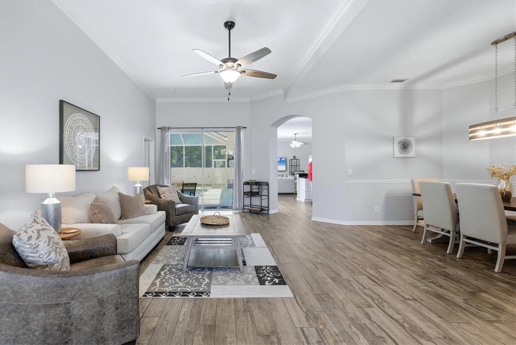A living room with wood-look tile flooring, a ceiling fan, and an adjacent dining area — 4617 EGMONT DRIVE, BRADENTON, FL