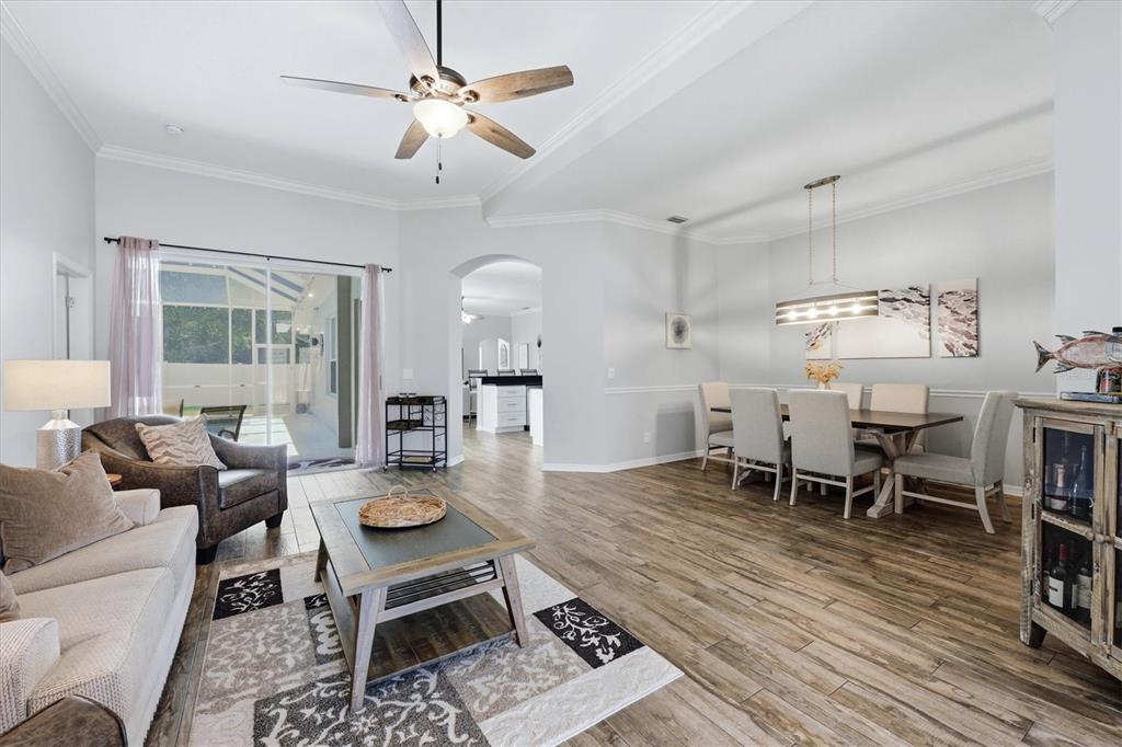 An open-concept living and dining area features wood-look tile flooring and a ceiling fan — 4617 EGMONT DRIVE, BRADENTON, FL