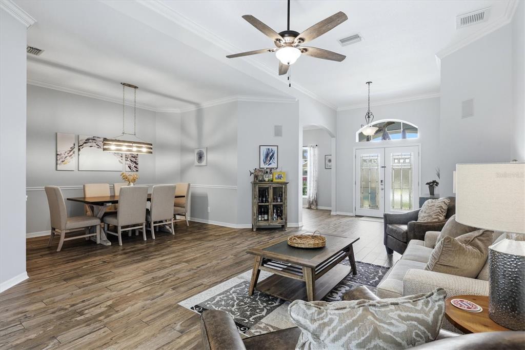 An open-concept living and dining area features wood-look tile flooring, a ceiling fan, and furniture — 4617 EGMONT DRIVE, BRADENTON, FL