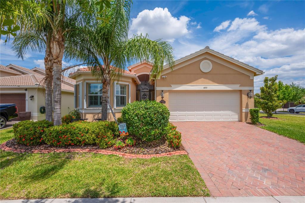 A single-story house with a brick driveway, a palm tree, and a two-car garage — 4853 GRAND BANKS DRIVE, WIMAUMA, FL